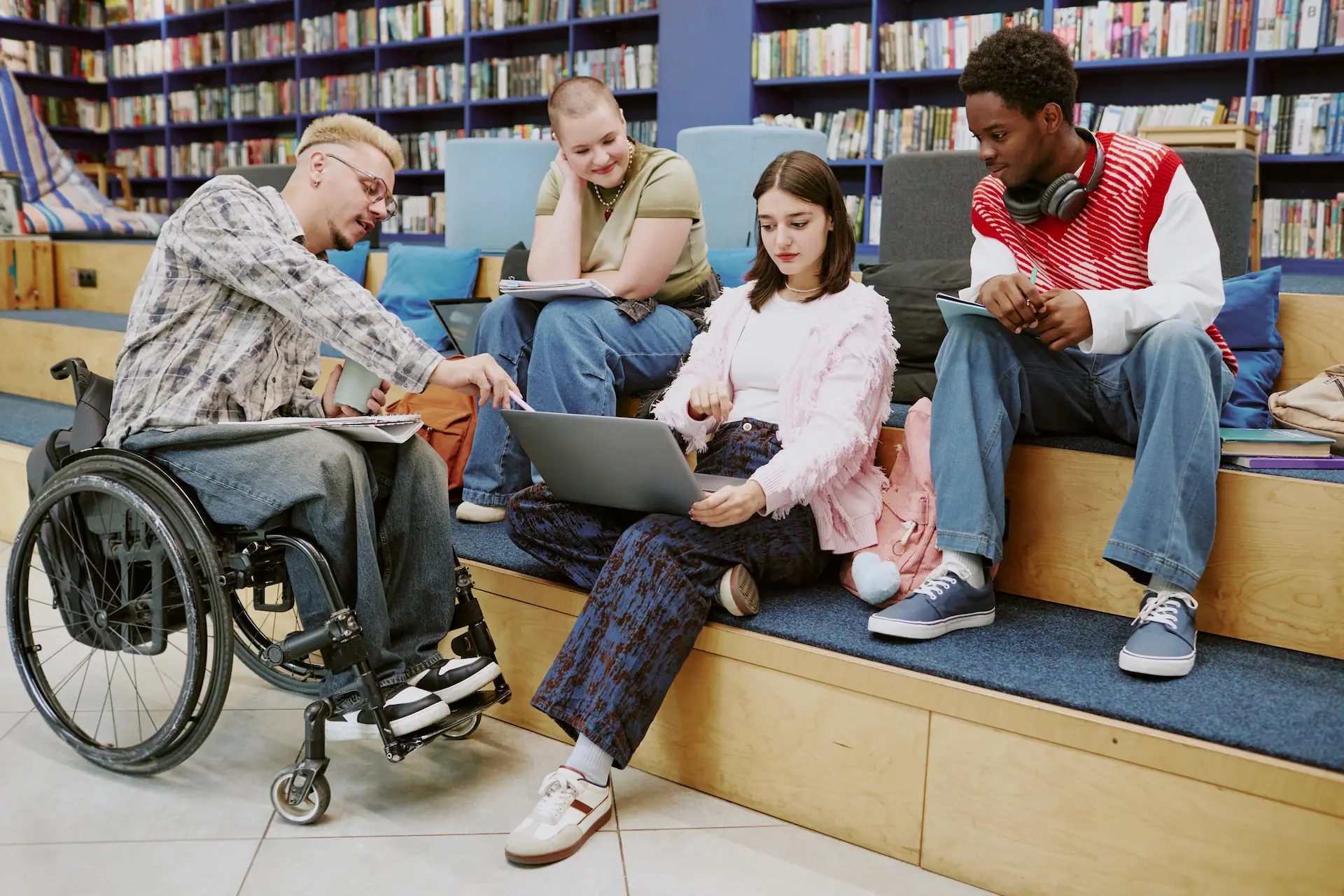 Three diverse students collaborating in a modern library, highlighting accessibility and inclusion.