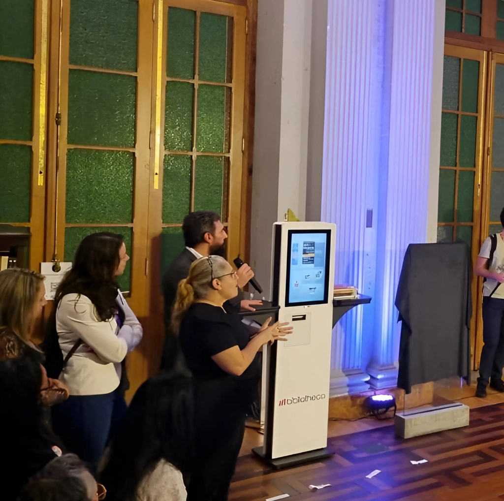 Executivo da Bibliotheca, João Ramos, demonstra o funcionamento do quiosque de autoatendimento selfCheck 600eco durante cerimônia na Biblioteca Pública do RS